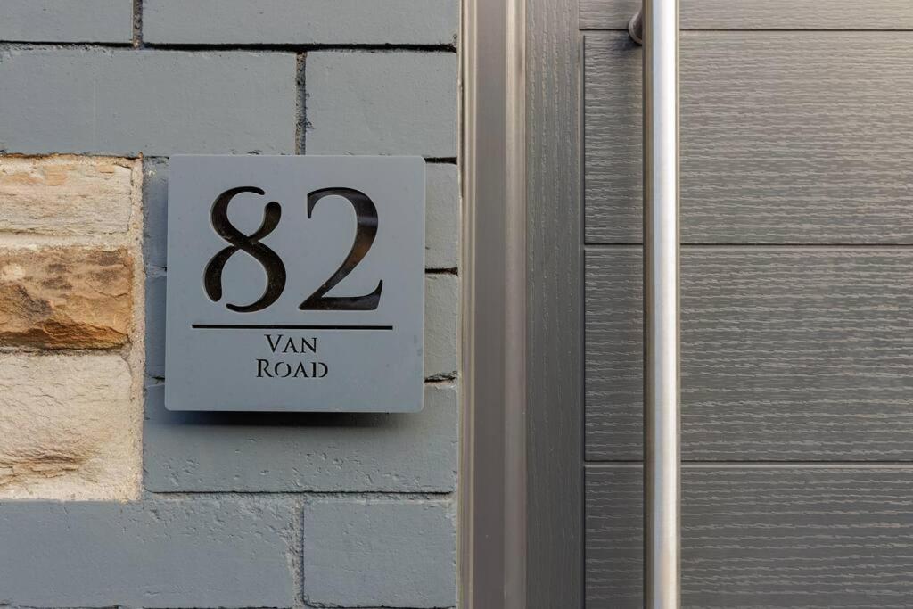 een bord aan de zijkant van een stenen muur met bij 82 Van Road in Caerphilly