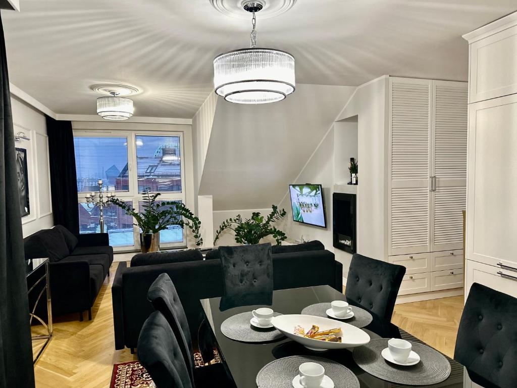 uma sala de estar com um sofá, uma mesa e cadeiras em Apartament Szafarnia DeLux em Gdansk