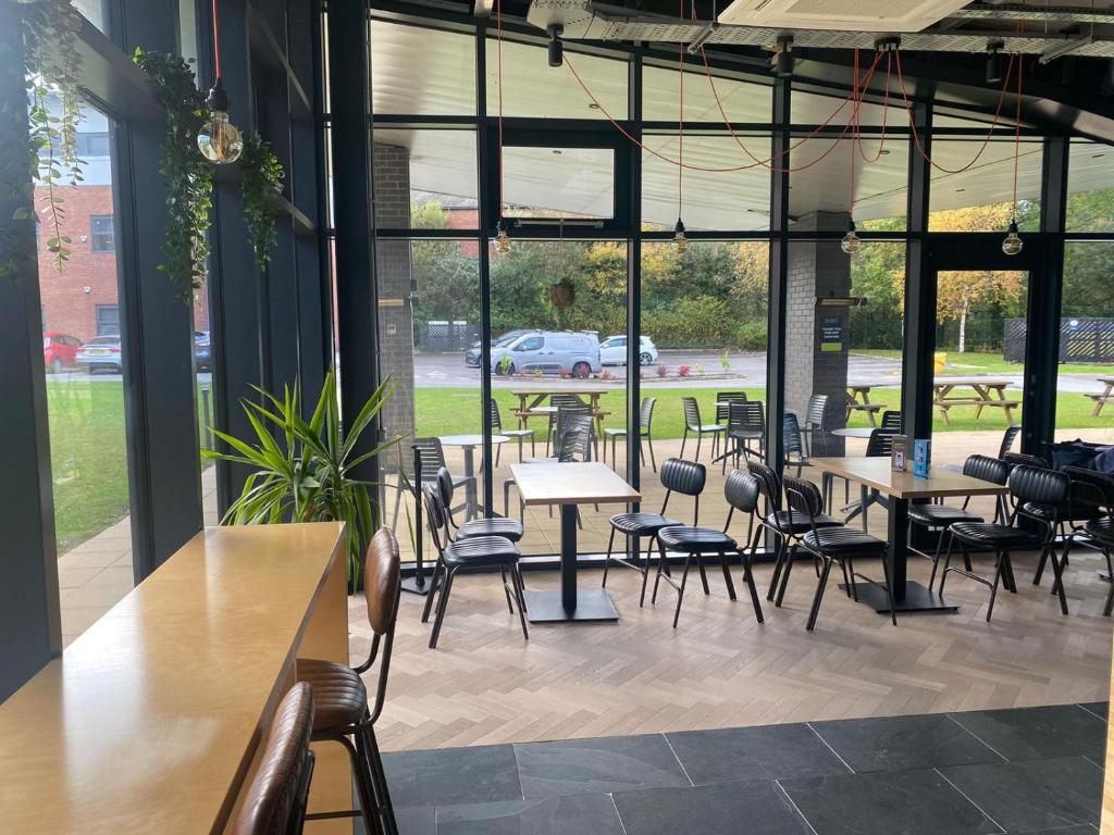 um restaurante com mesas e cadeiras e muitas janelas em Cosy living em Camberley