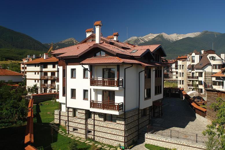 a white house with a red roof and some buildings at Winslow Elegance Apartments in Bansko