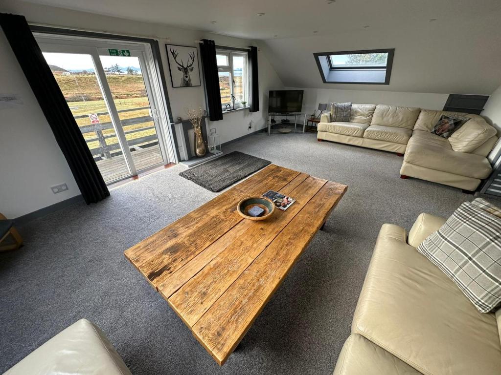 a living room with a wooden table in the middle at Self Catering Spacious open plan 3 bed apartment with sea views in South Erradale