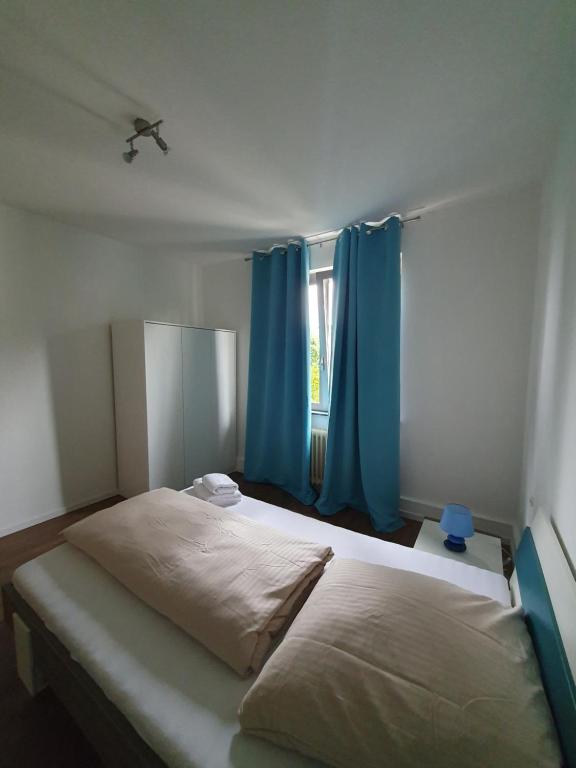 a bedroom with a large bed with blue curtains at Privatzimmer an der Uniklinik Mainz, sehr zentral in Mainz