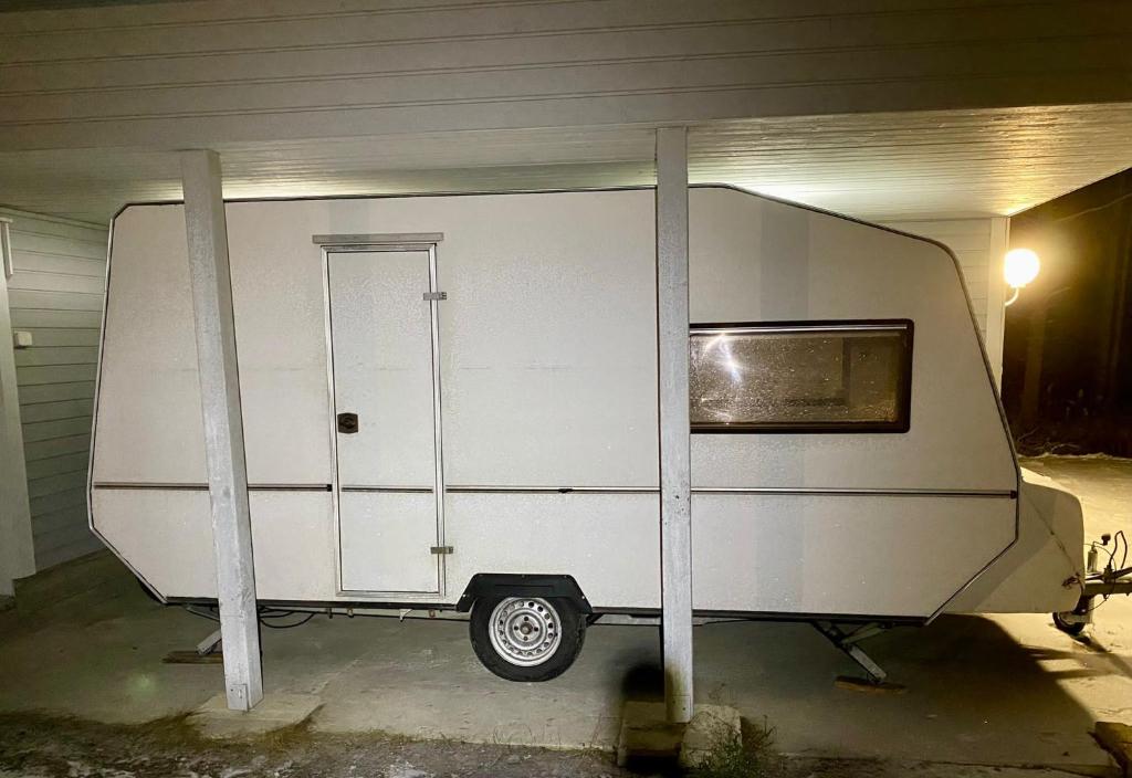 a white trailer in a garage with two poles at Garden Caravan in Rovaniemi