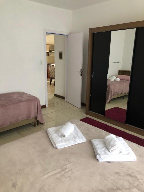 a bedroom with two white towels on the floor and a mirror at Casa vermelha, sitio pousada vô maneca in Timbó
