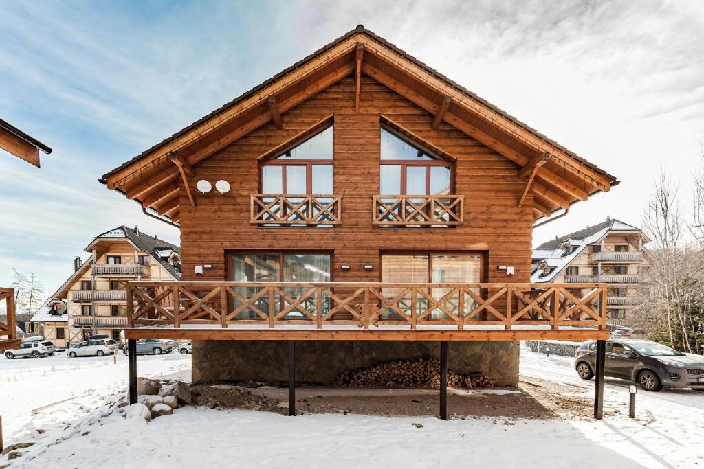 a log home with a deck in the snow at Chalets Royal, Tatranská Lomnica in Vysoke Tatry - Tatranska Lomnica.