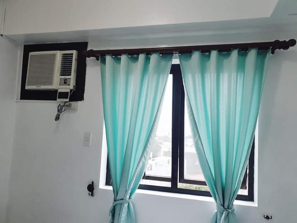 Cette chambre dispose d'une fenêtre avec des rideaux bleus. dans l'établissement Studio Unit Persimmon Condominium, à Cebu