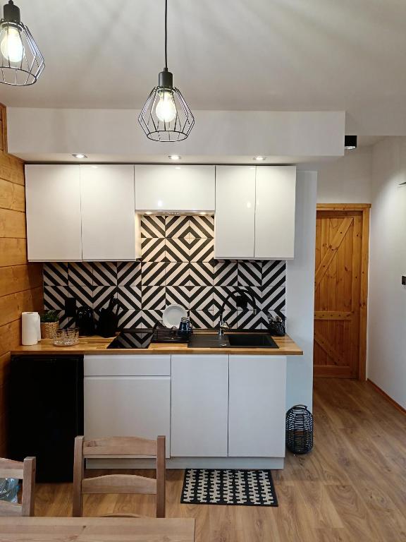 a kitchen with white cabinets and a patterned wall at Raj nad Narwią in Zatory