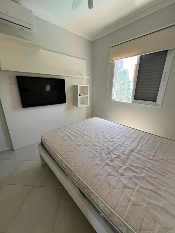 a bedroom with a bed and a flat screen tv at Apartamento Praia Grande 405 in Ubatuba