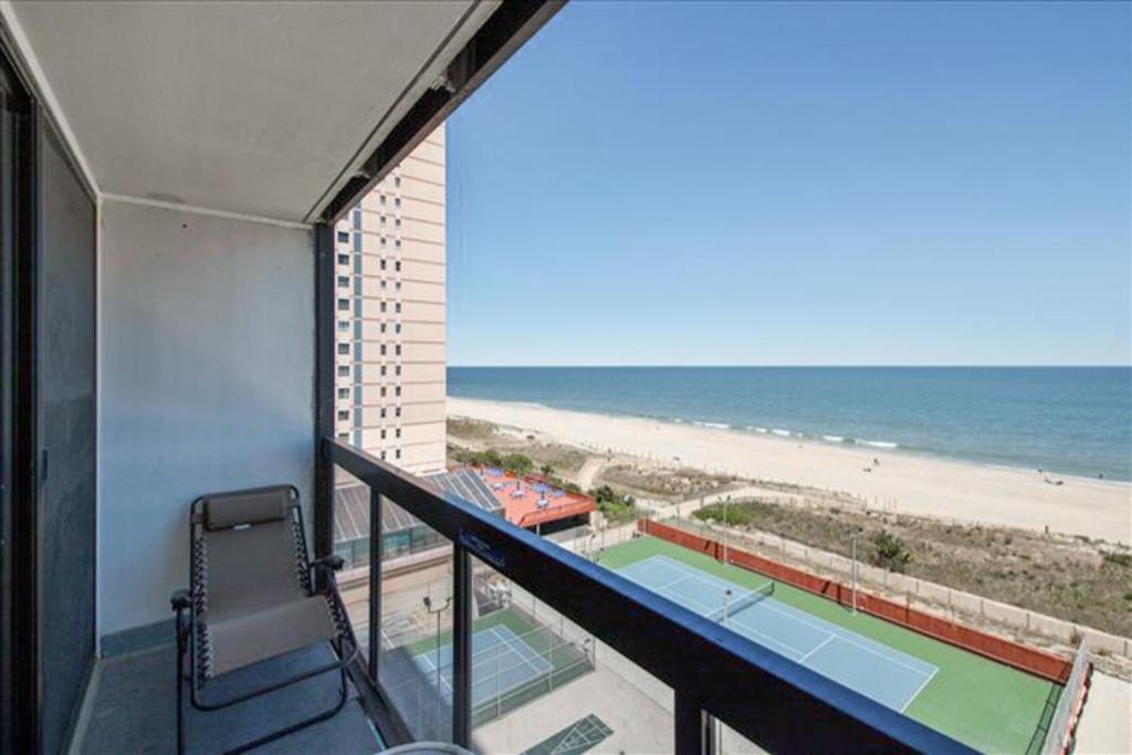 a balcony with a view of a tennis court and the beach at Golden Sands 605 in Ocean City