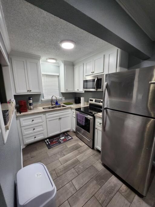 una cocina con nevera de acero inoxidable y armarios blancos en Blue Shark *H14* @ Montrose Elegant 1BR King Apartment, en Houston