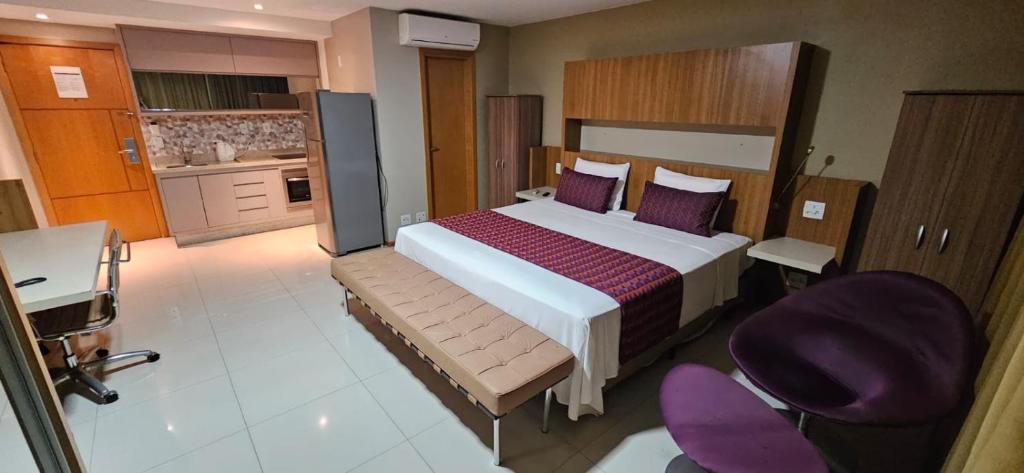 a bedroom with a large bed and purple chairs at Flat de luxo no Jade Park Sul Brasília-DF in Brasilia