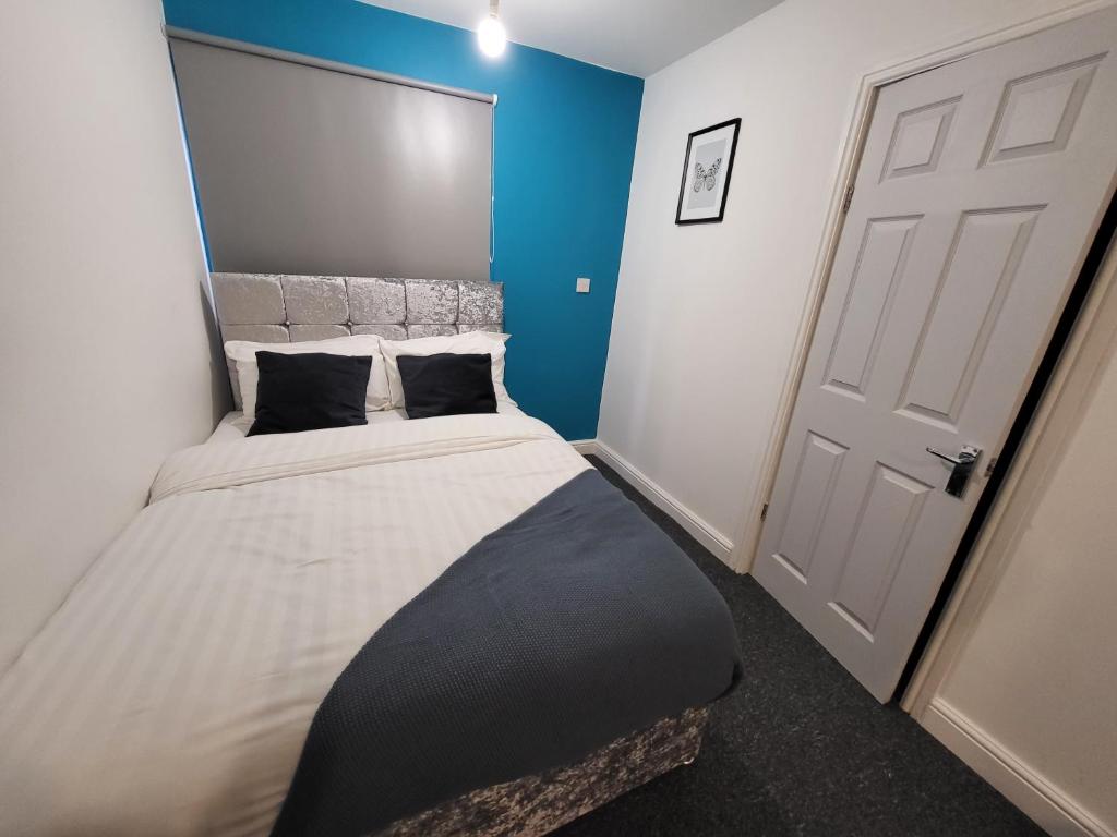 a bedroom with a large bed with a blue wall at Premier Studios Nottingham - Tring Vale in Nottingham