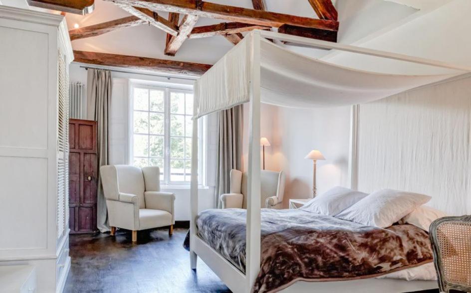 Les ÉcrennesにあるLe Manoir de Villefermoyのベッドルーム(白い天蓋付きベッド1台、椅子付)