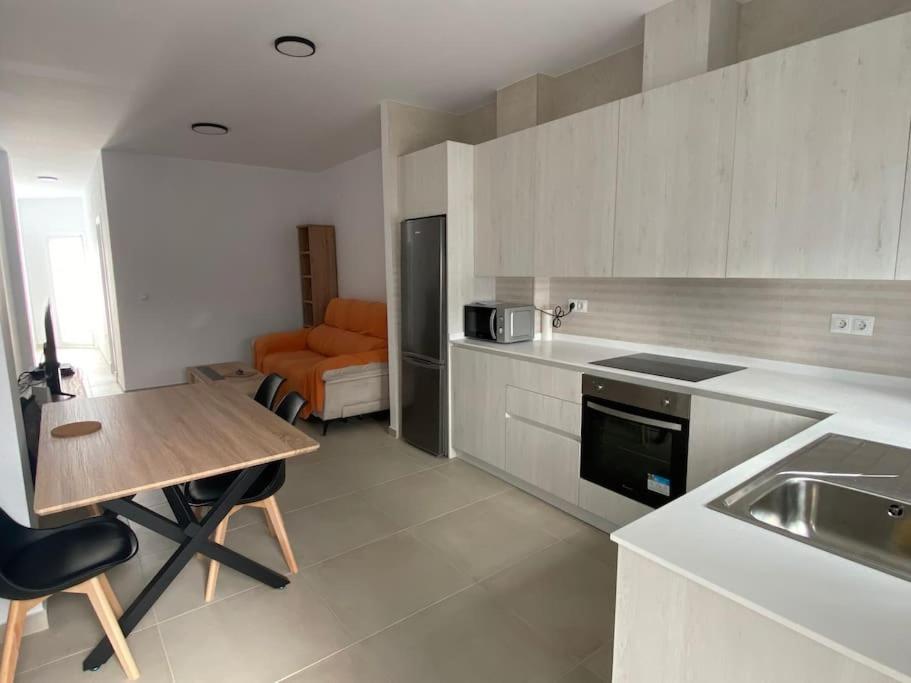 a kitchen with a wooden table and a dining room at Chic Comfort Apt in Chiclana Downtown by Chiclana Dreams in Chiclana de la Frontera