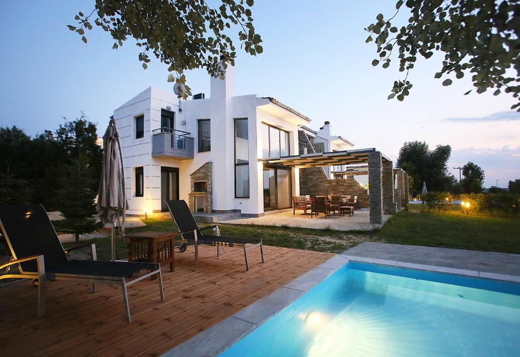a villa with a swimming pool in front of a house at Sunny Sani Luxury Villas in Sani Beach