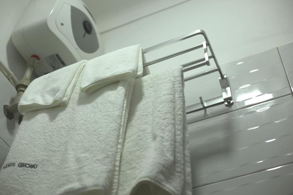 a towel rack with white towels on it at Orchid Suites, Kira in Bulindo