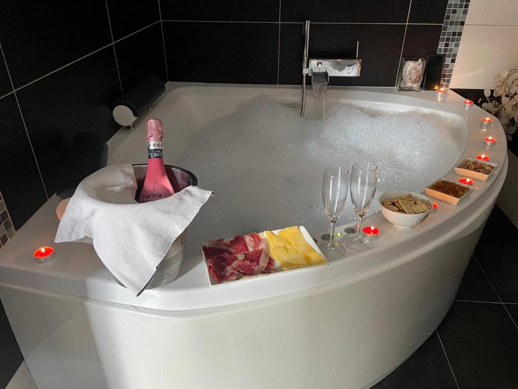 een bad met een fles champagne en wijnglazen bij Casa con jacuzzi y piscina con vistas al castillo in Corbera de Alcira