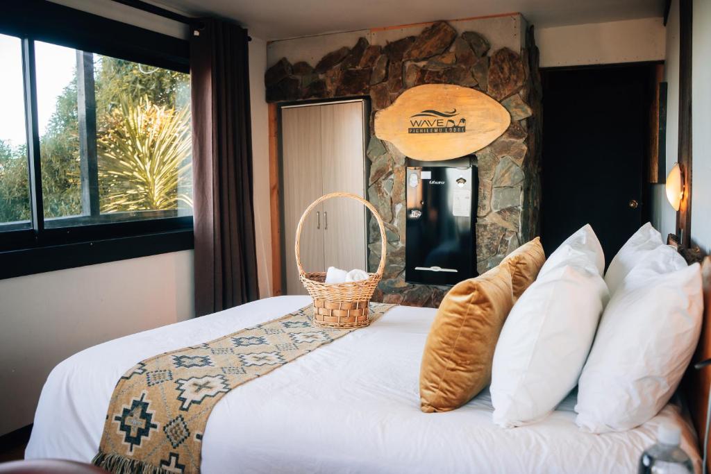 1 dormitorio con 1 cama con pared de piedra en Moana Pichilemu Lodge, en Pichilemu