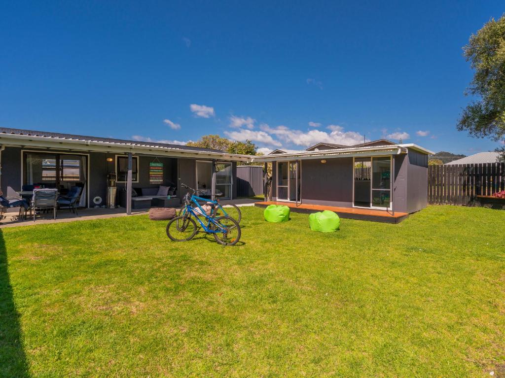 a house with a bike parked in the yard at Walk to the Water - Whangamata Holiday Home in Whangamata