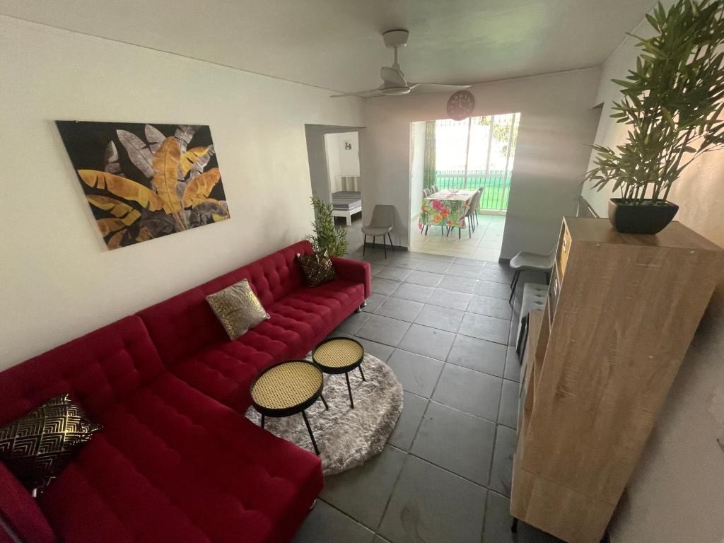 uma sala de estar com um sofá vermelho e uma mesa em Le Cocon Des Îles em Les Abymes