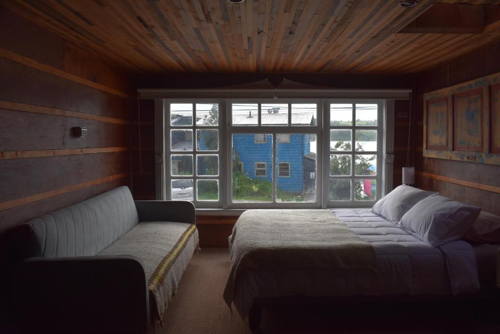 Un dormitorio con una cama y un sofá y una ventana. en Estación Hostel, en Castro