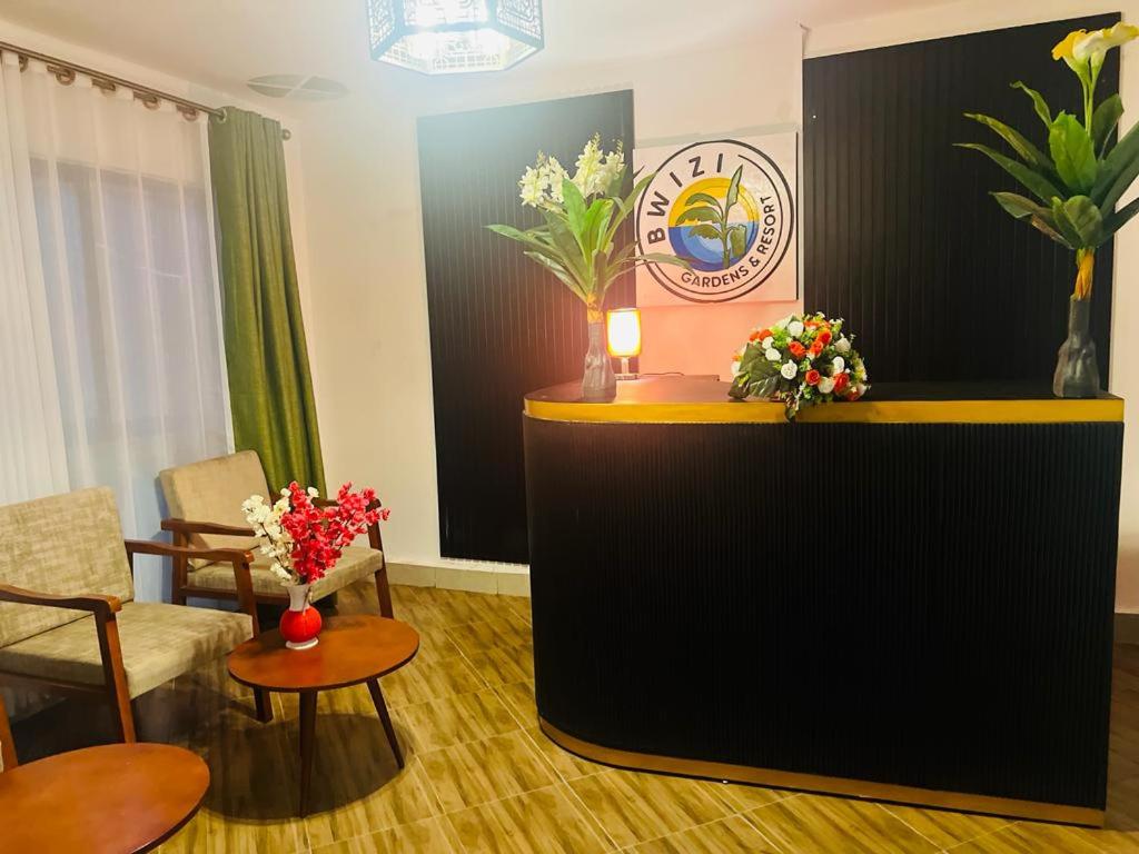 Bwizi Resort and Gardens في Kanyigiri: غرفة بها مكتب استقبال وبه زهور