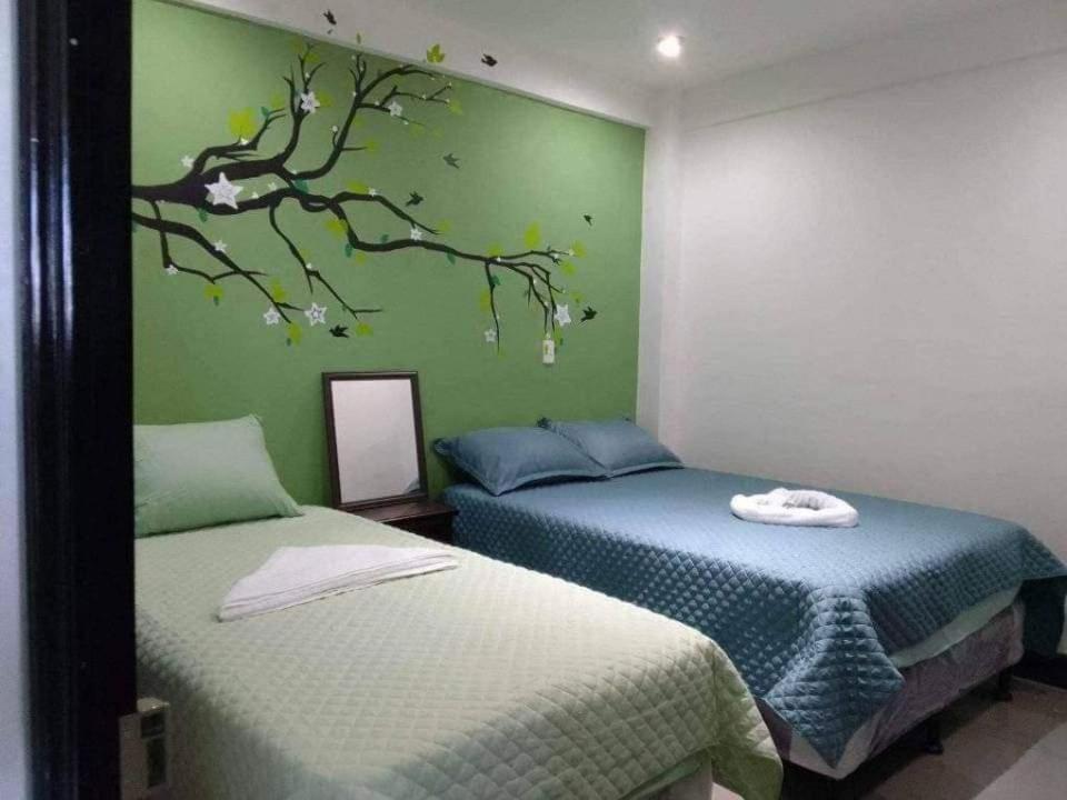 2 letti in una camera con parete verde di Q´ojoom Jaay a San Juan La Laguna