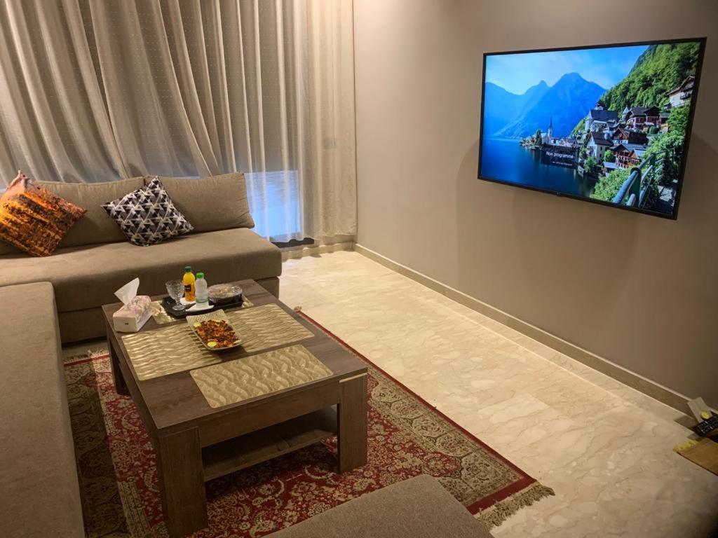 a living room with a couch and a tv on the wall at Studio haut standing convivial et bien équipé au coeur de Casablanca in Casablanca