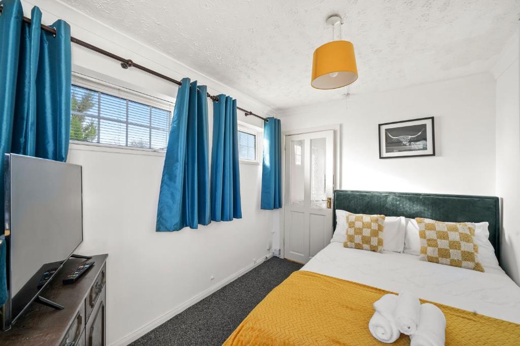 a bedroom with blue curtains and a bed and a television at 1 bedroom flat Aylesbury, Private Parking, Fowler rd in Buckinghamshire