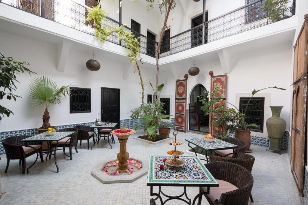an outdoor patio with tables and chairs and plants at Origin Hotels Riad Lhena in Marrakech