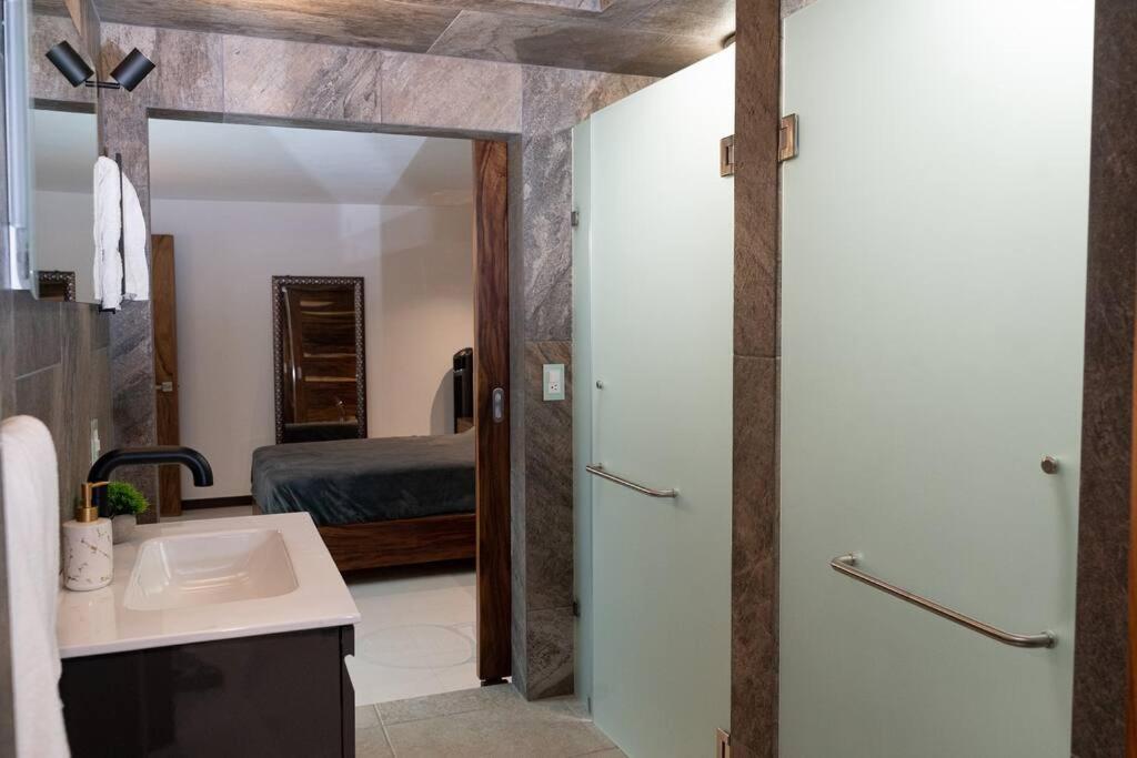 een badkamer met een wastafel, een douche en een bed bij Árbol de Guanacaste in Zitácuaro