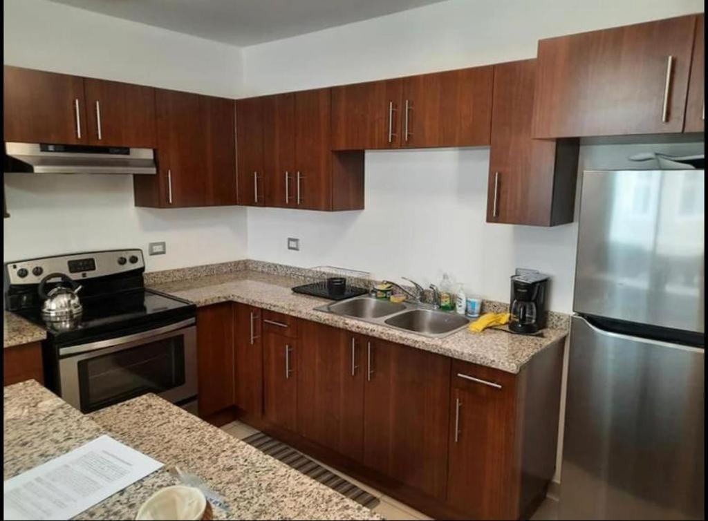 a kitchen with wooden cabinets and a stainless steel refrigerator at Los Próceres Apartamento Zona Exclusiva in Tegucigalpa