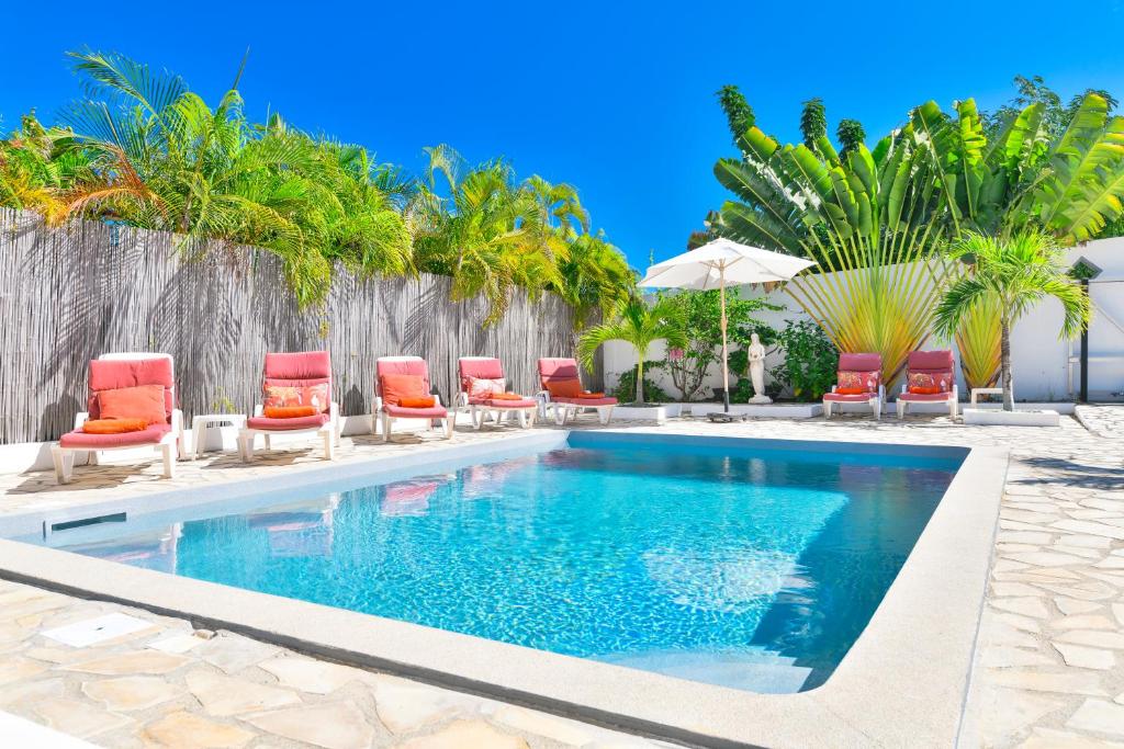 una piscina con sillas y sombrillas en Villa Caribbean Star, 5 min walk from the beach en Orient Bay