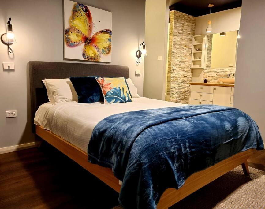 a bedroom with a bed with a blue blanket on it at Jasmine Escape - WITH SPA, home in heart of Hunter in Ellalong