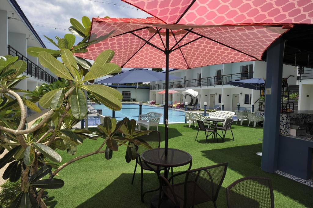 Maribago的住宿－CASABLU HOTEL&RESORT，庭院配有桌椅和遮阳伞。