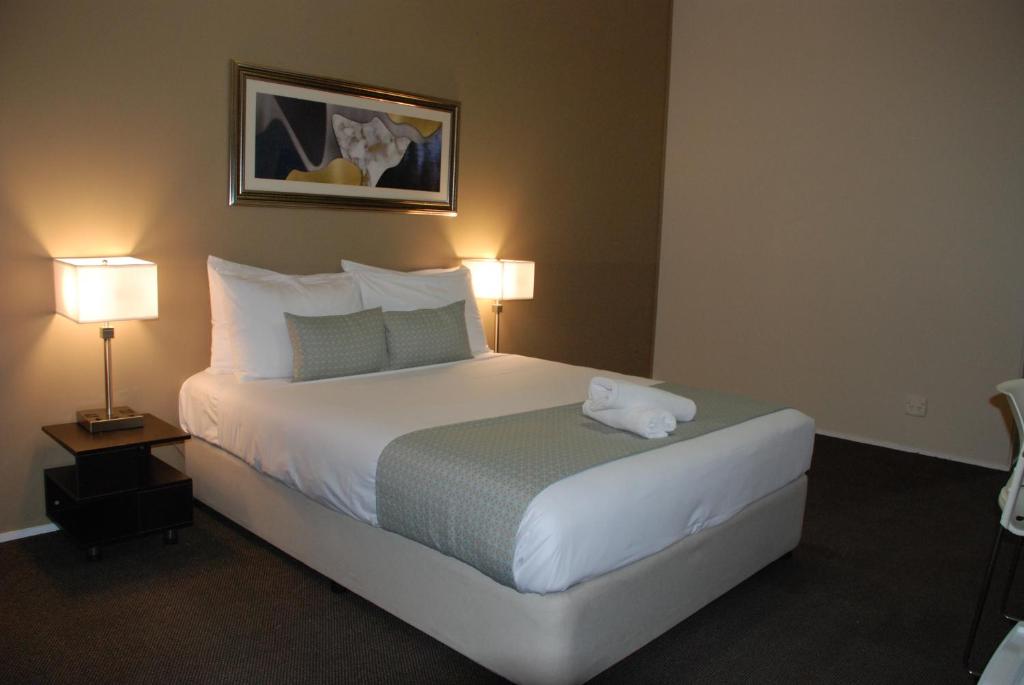 a hotel room with a large bed with two lamps at Airport Gateway Hotel in Auckland
