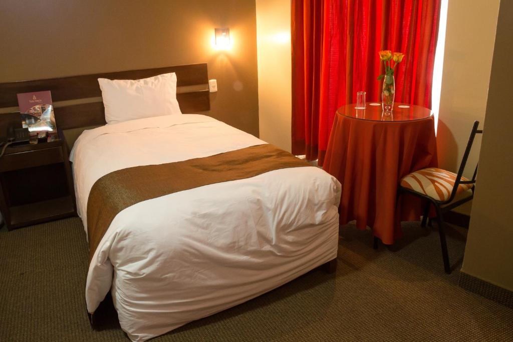 a hotel room with a bed and a red curtain at UTASA VILLAREAL Inn in Puno