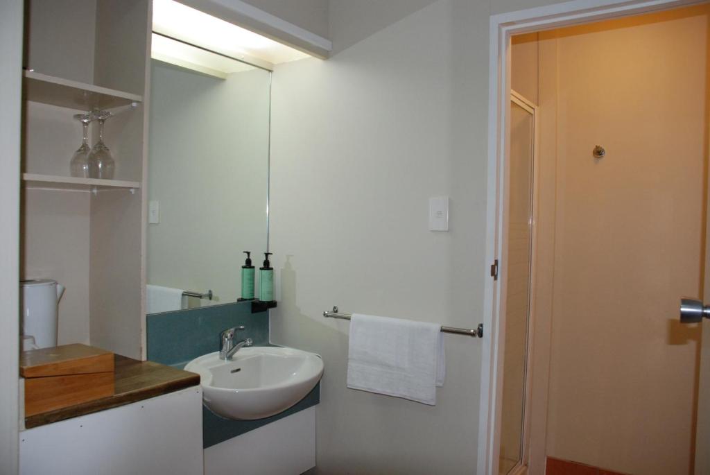 a white bathroom with a sink and a mirror at Airport Gateway Hotel in Auckland