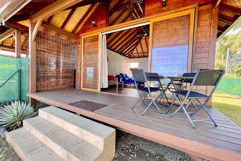 una terraza de madera con mesa y sillas. en Blackstone Paea Premium beachfront bungalow private access wifi - 3 pers, en Paea