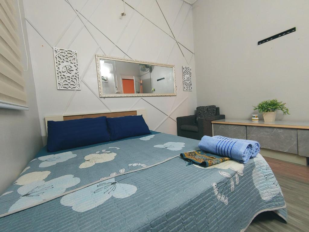 Schlafzimmer mit einem Bett mit blauer Decke und einem Spiegel in der Unterkunft Tasek Homestay D Village Ipoh in Ipoh