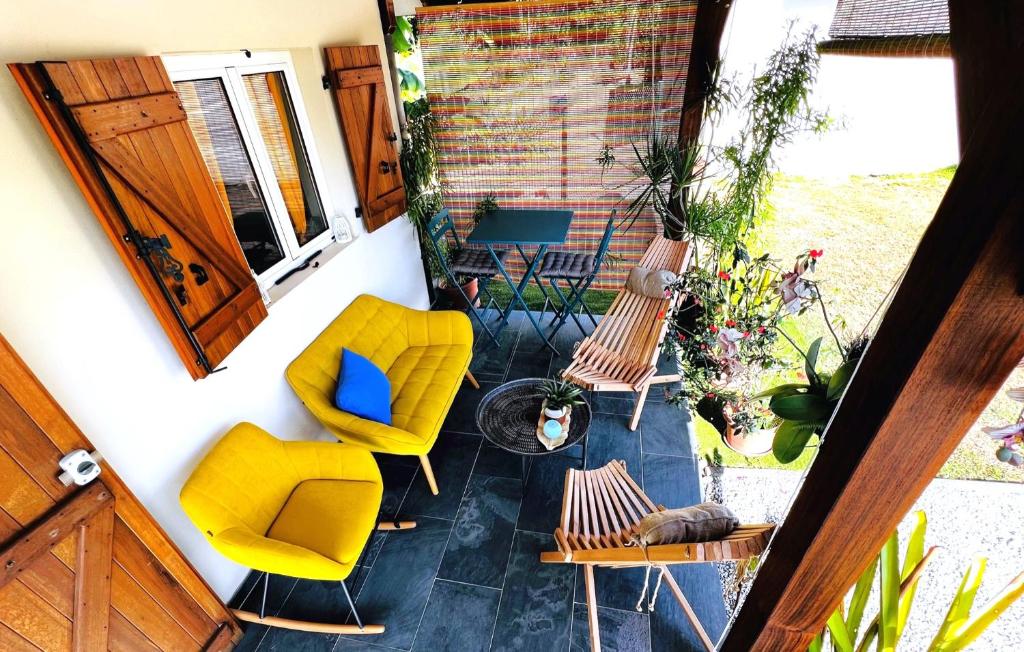 a patio with yellow chairs and a table and a window at La Villa Louisia in Matoury