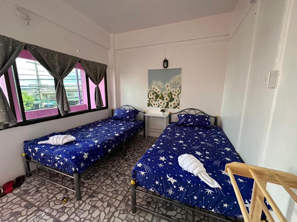 a bedroom with two beds and a table and windows at Madam Guesthouse in Krabi town