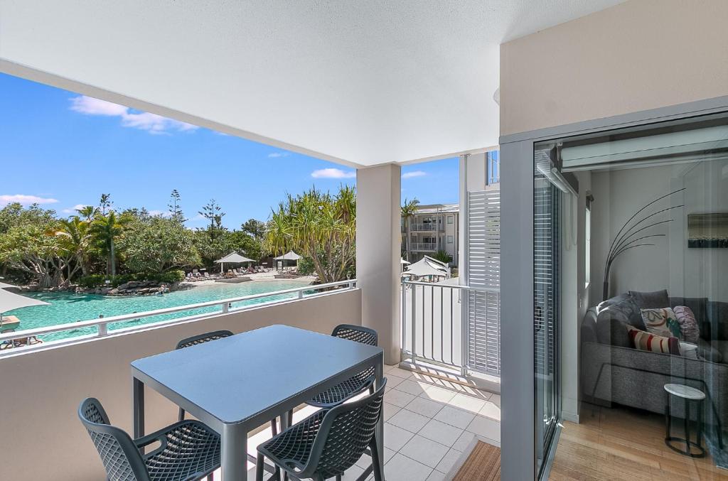 a balcony with a table and chairs and a view of the pool at Pool View Apartments at Peppers Salt Resort by uHoliday 2BR 1BR and Hotel Room Options Available in Kingscliff