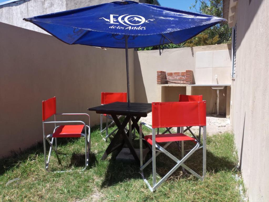 a table with four chairs and a blue umbrella at Salta 869 in Mar de Ajó