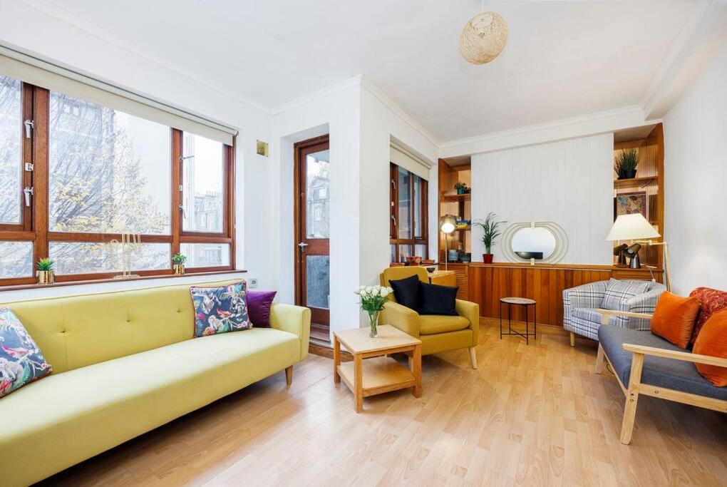 een woonkamer met een gele bank en stoelen bij Kings Cross Suite in Londen