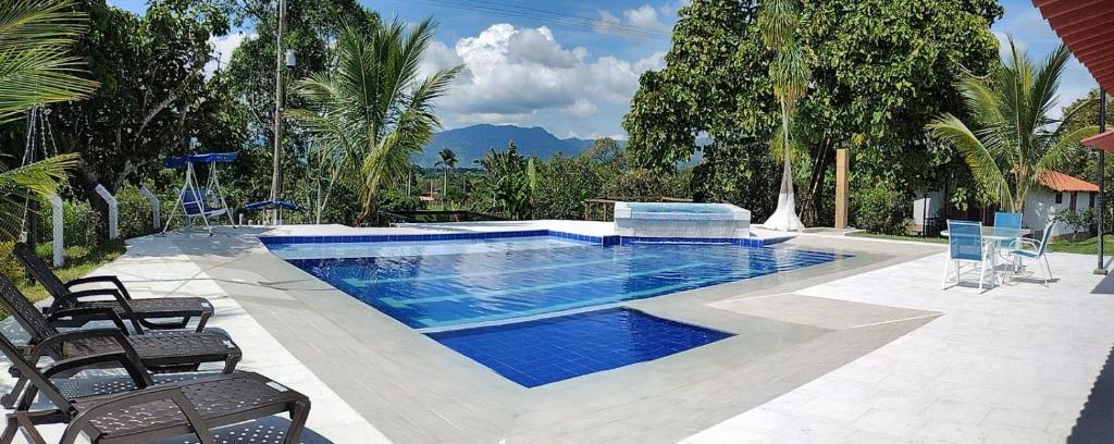 una piscina con 2 sillas y una mesa en FINCA HOTEL LA BONITA BY LA MACORINA, en Quimbaya