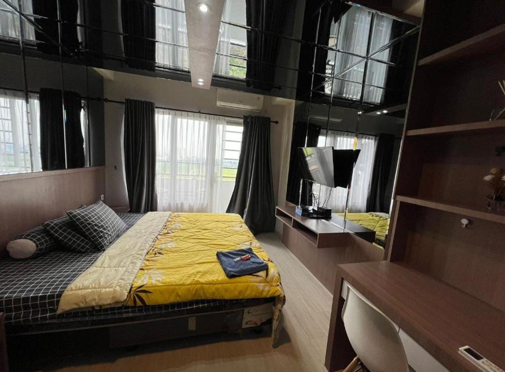 a bedroom with a bed with yellow sheets and a mirror at Skyview Setiabudi Apartment in Sunggal