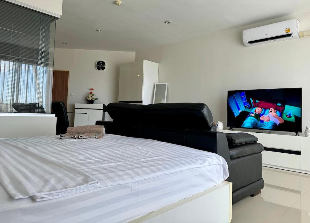 a bedroom with a bed and a flat screen tv at Thawi Studio with Sea View in Chic Condo in Karon Beach