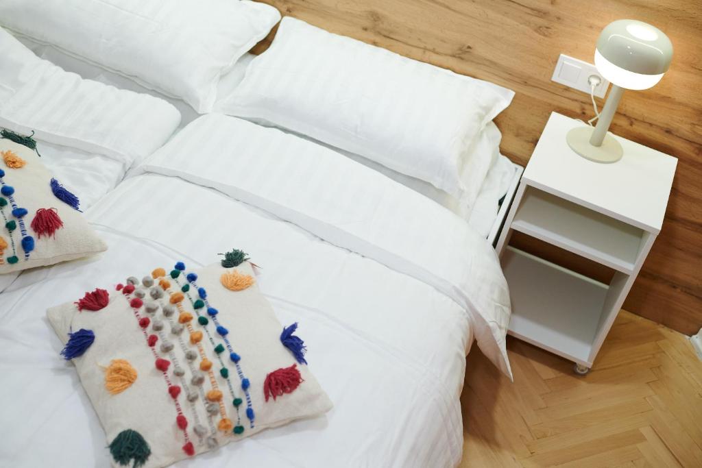 - un lit blanc avec des oreillers blancs et une table de nuit blanche dans l'établissement Lama Hostel, à Ivano-Frankivsk
