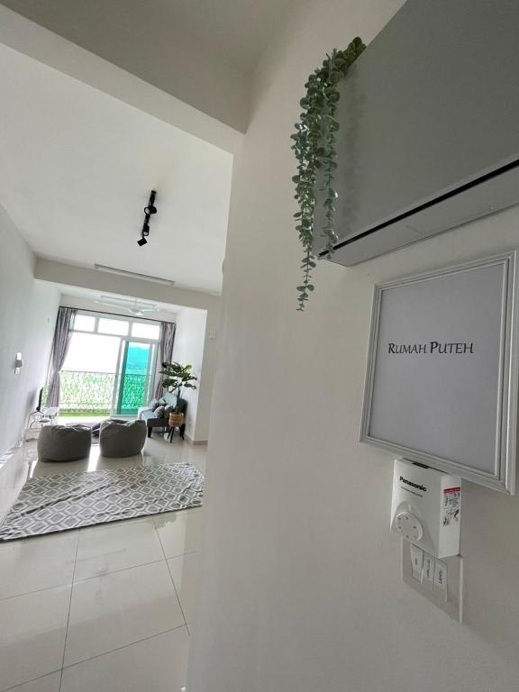 a living room with a couch and a tv on a wall at Rumah Puteh Homestay in Ipoh
